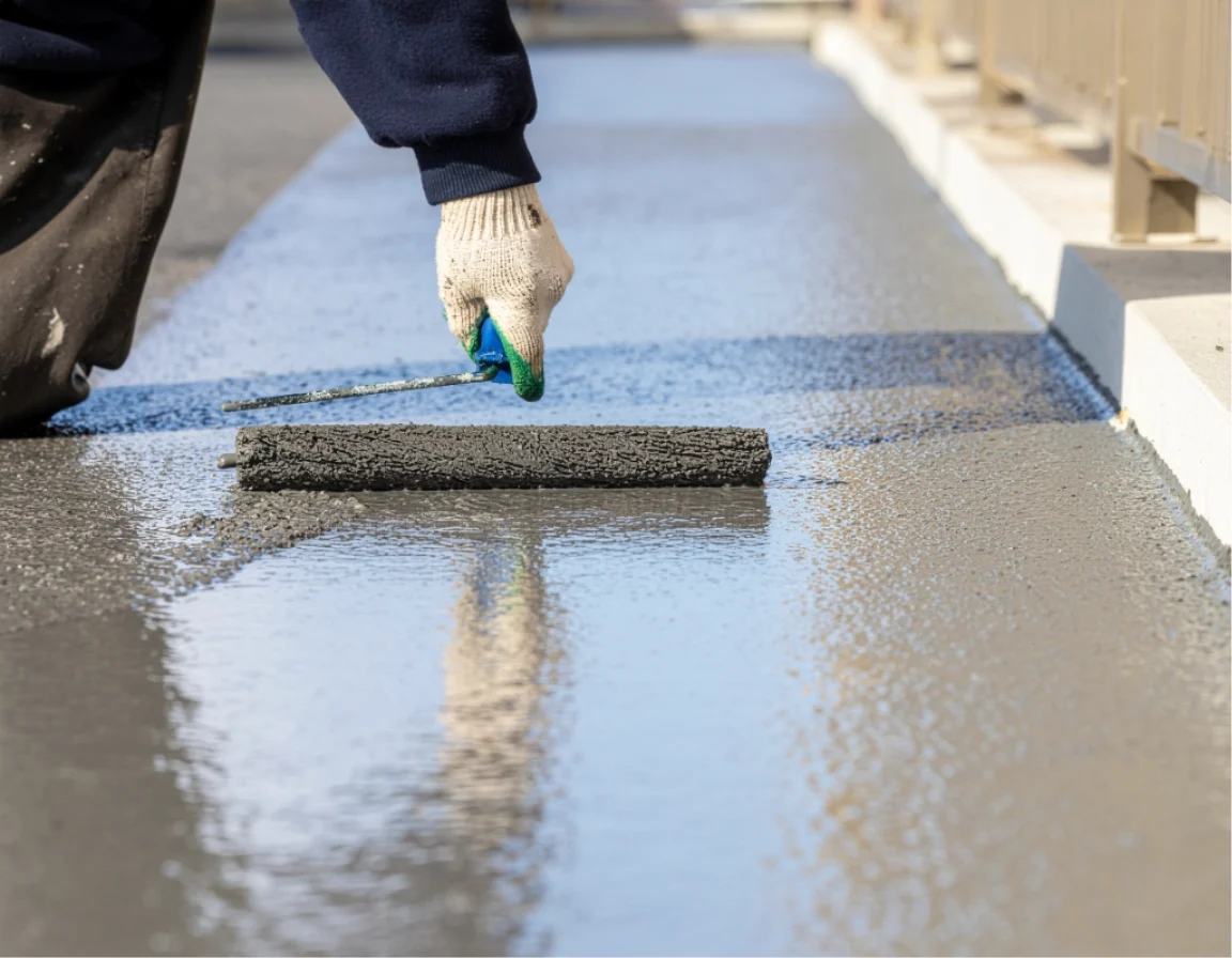 白手袋をした職人がブルー系防水材を専用工具で建物外壁に丁寧に塗布・施工している詳細なクローズアップ。